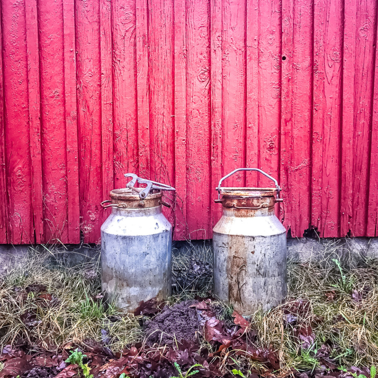 Milchkannen warten neben dem Haus
